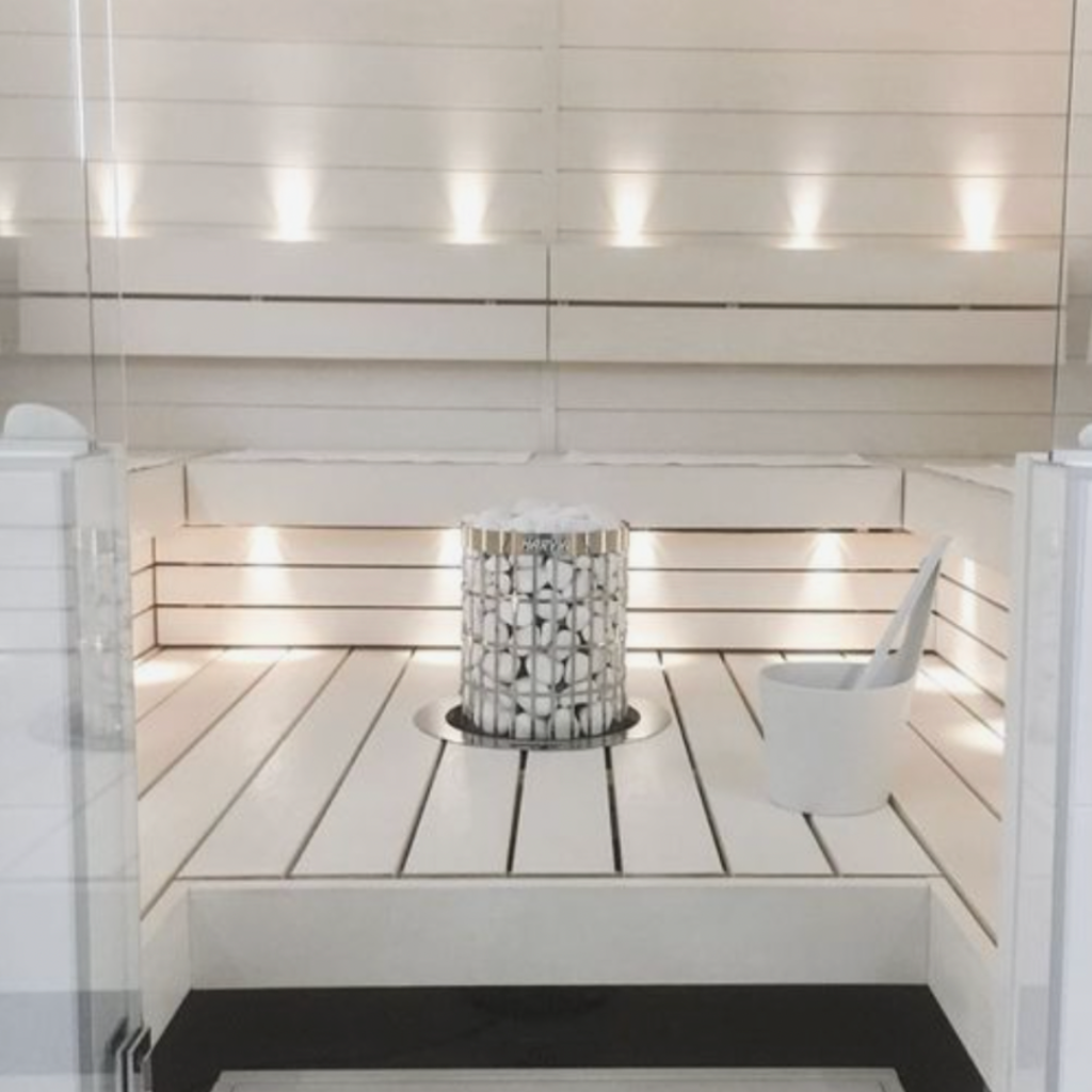 All-white sauna with white stove with white stones in the center